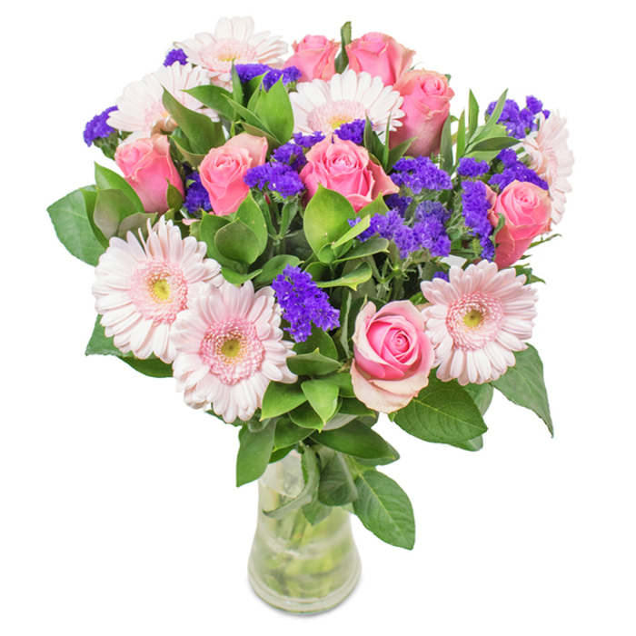 A meticulously arranged floral display stands proudly in a transparent glass vase, its vibrant blooms softly illuminated against a pristine white backdrop - a vision that evokes the charming serenity of Noak Hill. The arrangement features an exquisite interplay of around 7 to 9 medium pink roses, showcasing the classical beauty of tightly swirling petals and softly blushing hues. Complementing these are 5 to 7 pale pink gerbera daisies, their generous, round faces and gently radiating petals capturing early morning sunlight as it streams through the borough's quiet streets. Throughout the bouquet, vivid clusters of purple statice provide lively visual texture and a deeper colour counterpoint, recalling wildflowers from the hedgerows that border Noak Hill Common. Abundant, rich green foliage fans out at the base, creating an oasis of freshness that frames and accentuates every bloom, and suggesting both abundance and tranquillity. The polished clarity of the glass vase reveals the clean stems and sparkling water within, infusing the arrangement with a palpable sense of natural vitality. This composition, ready for same-day delivery across Noak Hill via Flower Delivery Noak Hill, is ideal for special celebrations-birthdays, anniversaries, Mother's Day-or as a refined addition to an office or family home, imparting feelings of joy, love, and heartfelt connection with every glance.